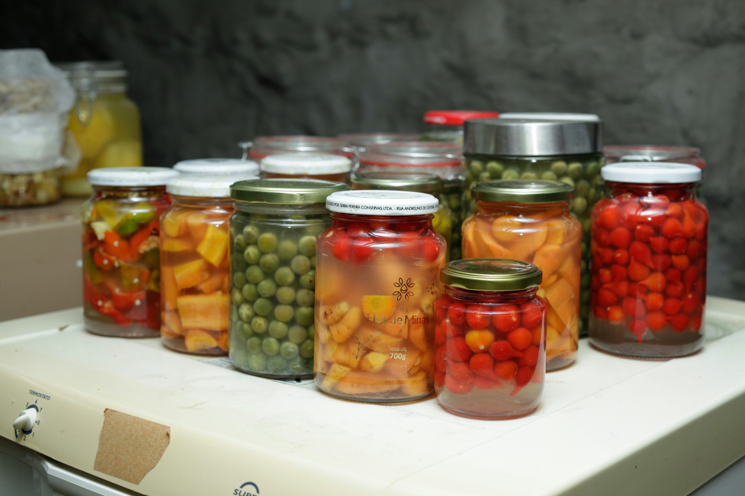 Mason jars filled with home-preserved peppers, carrots, peas, tomatoes, and strawberries — a full season of canning.
